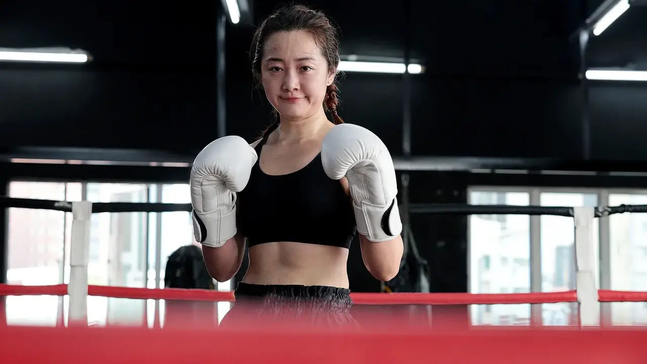 Female boxer standing confidently in the ring.