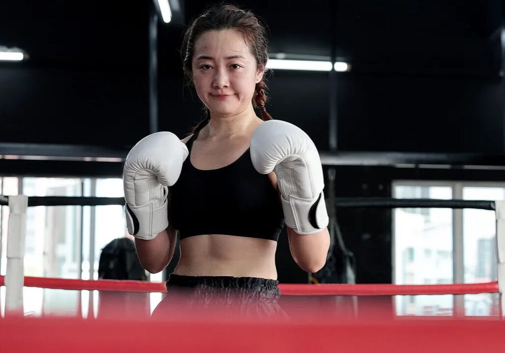Female boxer standing confidently in the ring.